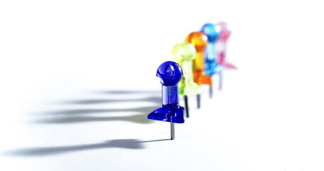 many colorful push pins on white, color concept