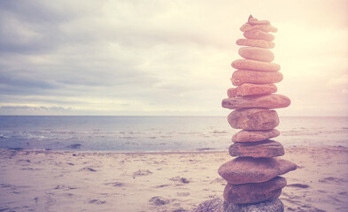 Fototapeta na wymiar Stone pyramid on a beach, zen, harmony and balance concept, color toning applied.