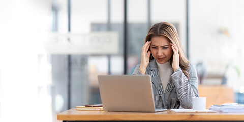 Fototapeta na wymiar Young businesswoman working on laptop stressed has a headache and thinks hard from work at the office