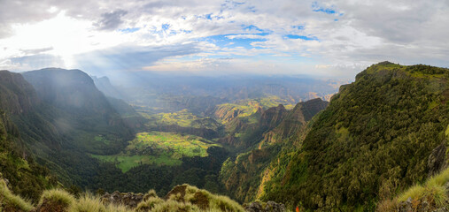 Panoramic view of valley and mountain landscape with clouds and sunrays coming through in the Simien Mountains Ethiopia, Africa