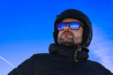 Blue sky and mountains reflected in skier's glasses, skier in the rays of the sun, winter in Italy, winter sports lover, mountains in winter. - obrazy, fototapety, plakaty