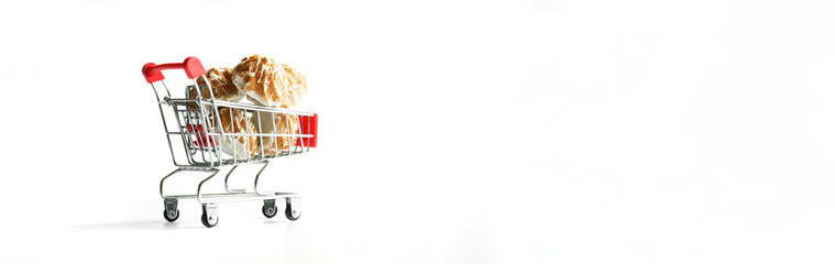 Delicious holiday sugar-glazed cupcakes in a miniature supermarket cart. The concept of buying sweets in a bakery or store and delivering groceries. Copy space. Web banner. White background