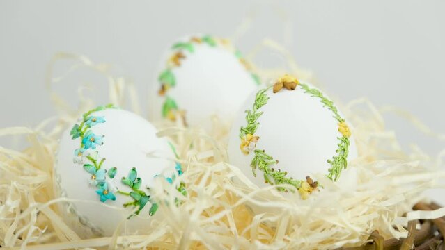 camera smoothly zooms away while shooting Three large goose ostrich turkey chicken eggs with ribbon embroidery on an eggshell in nest with sawdust handmade making embroidered eggs for Easter