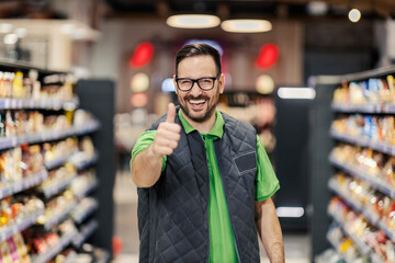 A supermarket manager is standing at marketplace and giving thumbs up while smiling at the camera. - Powered by Adobe