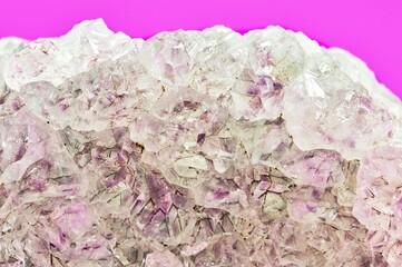 Light pale colored Amethyst quartz crystals in raw mineral form on a plain purple background.