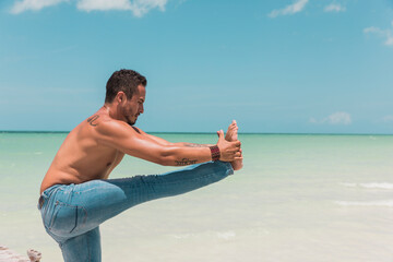 Man practicing yoga on the beach