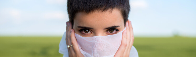 Portrait of a beautiful young woman in nature face covered with a white veil on  a sunny summer day	