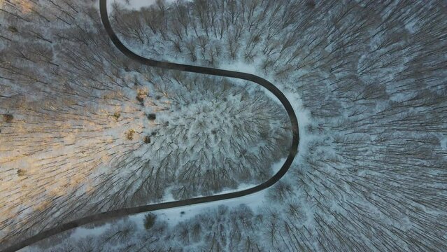 Aerial view of a serpentine road crossing a forest in wintertime with snow on Mount Terminio, Serino, Avellino, Irpinia, Campania, Italy.