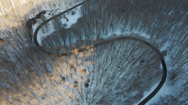 Aerial view of a serpentine road crossing a forest in wintertime with snow on Mount Terminio, Serino, Avellino, Irpinia, Campania, Italy.
