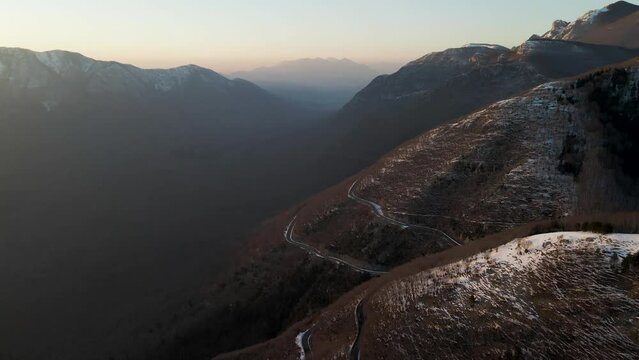 Aerial view of a scenic forest road on mountainside in wintertime at sunset with snow on Mount Terminio, Serino, Avellino, Irpinia, Campania, Italy.