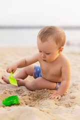 cute kid playing in the sandbox with toys on the seashore