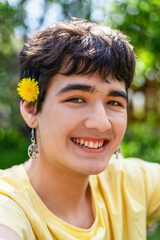 portrait of cute young man with flower in his hair and earrings in his ears, lgbt theme, pride