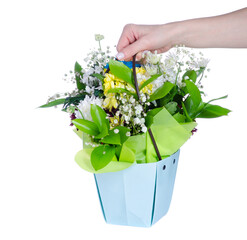 Basket bag with blue yellow white flowers in hand on white background isolation