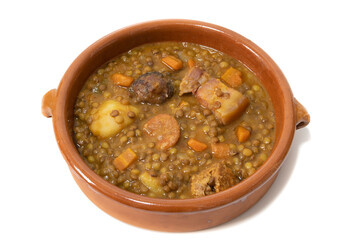 Lentil stew with chorizo, served in a clay bowl. Isolated on white background. Spanish food concept.