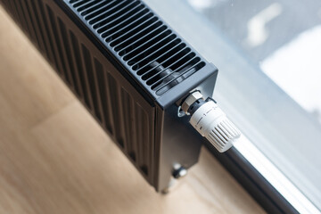 Detail of a modern black radiator under the window of a kitchen