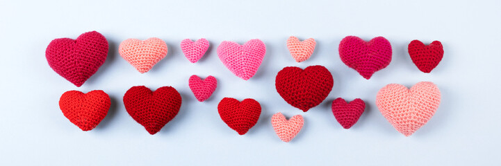 Multicolored crocheted hearts on a blue background. Happy Valentine's Day, Mother's Day and birthday greeting card. Banner, flat lay