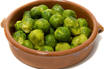 A pile of boiled brussels sprouts, served in a clay bowl. Isolated on a white background. Healthy food concept.