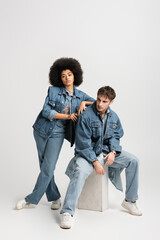 full length of brunette african american woman in sneakers standing near man in denim outfit on...