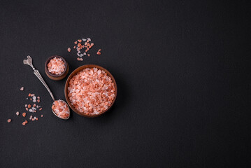Pink himalayan salt in a wooden bowl on a dark concrete background