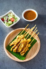 thai satay skewers with grilled pork and dipping sauces served on banana leaf plate