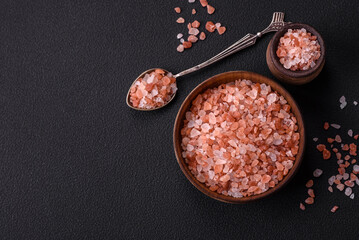 Pink himalayan salt in a wooden bowl on a dark concrete background