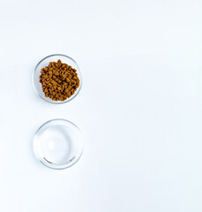 Dry pet food and water in glass cups on white background