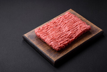 Raw beef or pork mince with salt spices and herbs on a wooden cutting board
