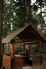 Fototapeta na wymiar portrait of a female tourist resting in a gazebo in the forest on hiking in the mountains