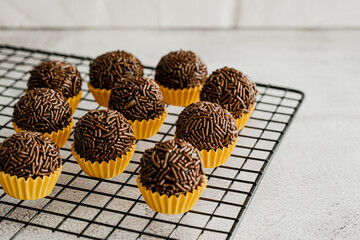 Brigadeiros de chocolate dentro da forminha amarela sobre grade preta em fundo branco