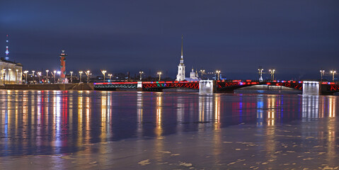 Fototapeta na wymiar Winter night landscape. Palace Bridge over Neva River on background of Rostral column and Peter and Paul Fortress. St. Petersburg