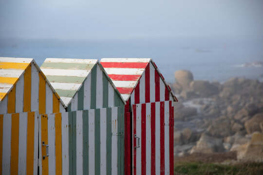 Des cabanes color&eacute;es dominent la plage du Gou&eacute;rou. La brume commence &agrave; envahir les rochers. 