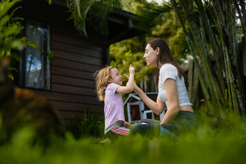 Fototapeta premium Happy young mother with her daughter at park sitting and playing and smiling
