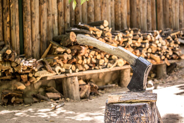 Firewood is split and stacked for the winter heating season. Background of stacked firewood, chopped wood for the stove. Ax for cutting wood.