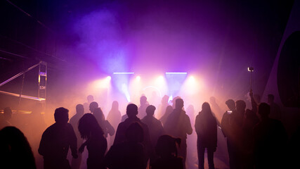 Obraz premium MOSCOW, Russia - February 2, 2023:Crowd dancing on a techno rave, streaming bright lights in a nightclub, cheerful vibe