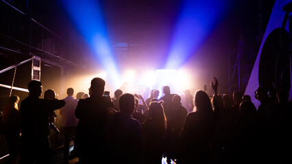 MOSCOW, Russia - February 2, 2023:Crowd dancing on a techno rave, streaming bright lights in a nightclub, cheerful vibe