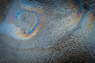 Colored texture of oil products on the asphalt in the rain.