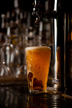 Beer foam overflowing around pint glass on brewery bar
