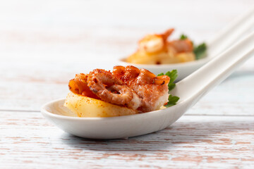Galician style octopus appetizers with potato in a ceramic spoon. Traditional Spanish tapa.