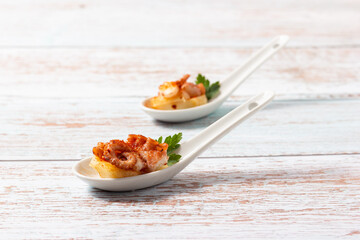 Galician style octopus appetizer with potato in a ceramic spoon. Traditional Spanish tapa.