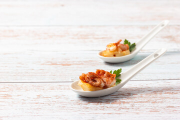 Tapa de pulpo a la gallega with potato in a ceramic spoon. Traditional Spanish tapa.