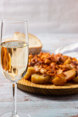 Glass of white sherry wine with a plate of Galician octopus in the background.