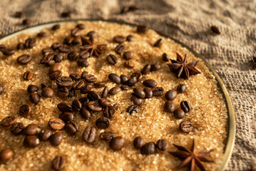 Coffee beans on brown sugar cane, lying on a bronze plate, against a background of coarse burlap. Background picture in brown tones