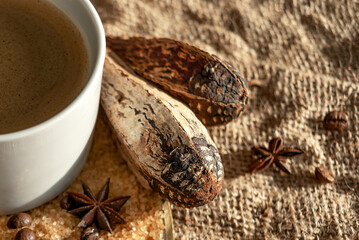 A bronze tray, with a cup of coffee, cane sugar and coffee beans, stands on a burlap