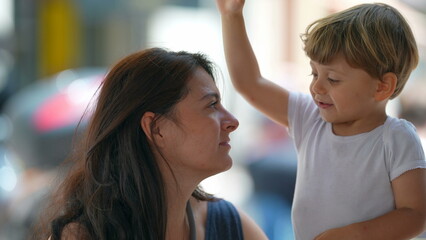 Child hitting mother head outside. Mom having patience. Parent tolerating little boy behavior. Parenting stress concept