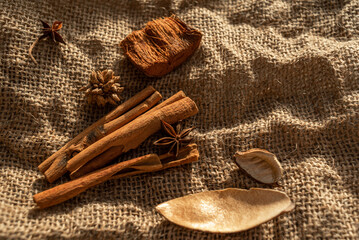 Fototapeta na wymiar A bunch of cinnamon sticks and anise stars on burlap. Dried flowers and pieces of bark