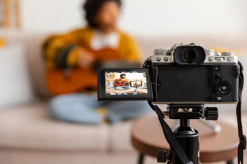 Blogger guitarist. African american girl blogger playing guitar talking to webcam recording vlog....