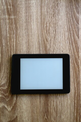 E-reader with blank screen on wooden table. Top view.