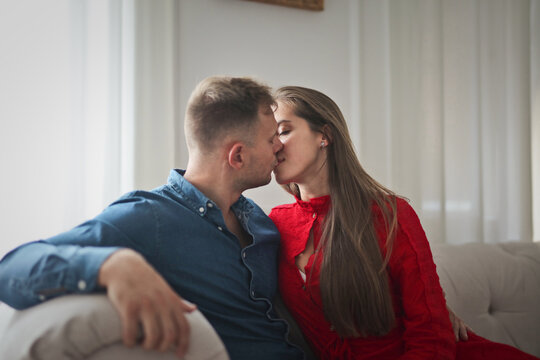 young couple kissing sitting on sofa at home