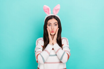 Photo of sweet impressed lady dressed striped pullover hare headband arms cheeks isolated teal color background