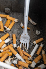 cigarette stubs with a plastic fork in a rubbish bin